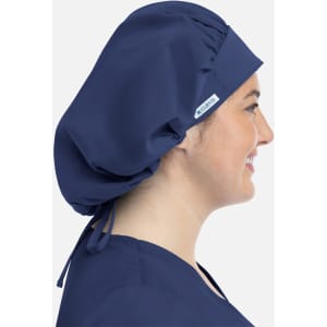 A unisex bouffant scrub cap in navy blue, worn by a model with a side profile. Features a logo.