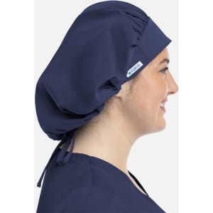 A navy unisex bouffant scrub cap displayed on a person, featuring a logo and adjustable ties at the back.