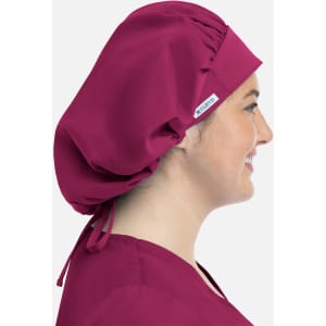 A unisex bouffant scrub cap in a rich burgundy colour, displayed on a model from a side profile.