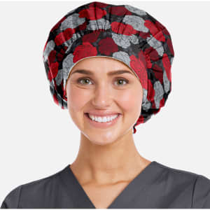 A printed unisex bouffant cap featuring a floral pattern in red and grey, worn by a smiling person in scrubs.