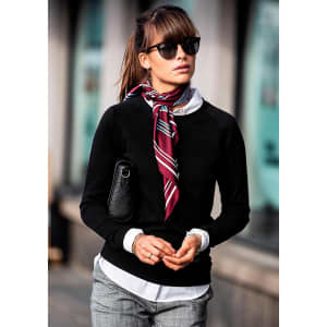 A black women's sweatshirt is worn with a white shirt underneath and a patterned scarf, paired with sunglasses and a handbag.