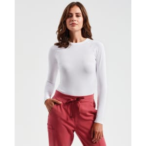 A long-sleeve white baselayer top displayed on a model, paired with pink trousers. The image features a logo.