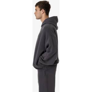 A grey garment dye plush fleece pullover hoodie on a model, featuring a relaxed fit and a hood.