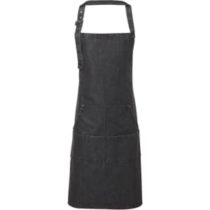 A dark denim bib apron with adjustable straps and three front pockets. Features a logo on the apron.