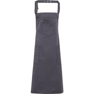 A dark grey Chino Cotton Bib Apron with pockets and a neck strap, featuring a logo.
