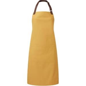 A mustard yellow bib apron with a brown leather strap and a front pocket, featuring a logo.