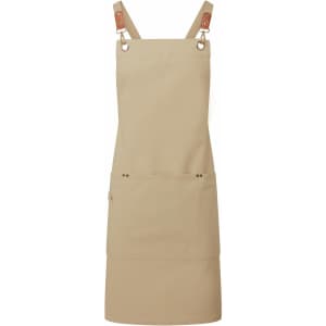 A tan cross-back bib apron featuring adjustable straps and a front pocket, with a logo on it.