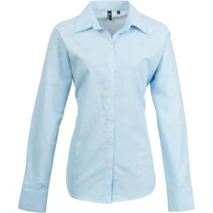 A light blue women's button-up Oxford shirt with long sleeves and a collar, featuring a logo.