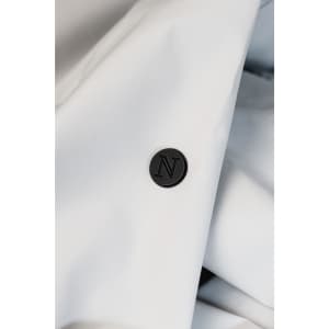 A close-up of a white jacket fabric featuring a black circular button with the letter "N" embossed on it.