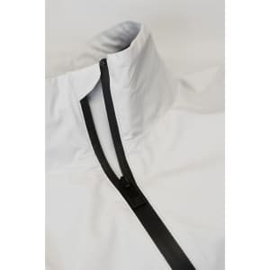 A white jacket with a high collar and a black zipper. Features a minimalistic design and has a logo.