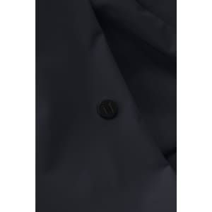 A close-up of a dark navy jacket featuring a round black logo button.