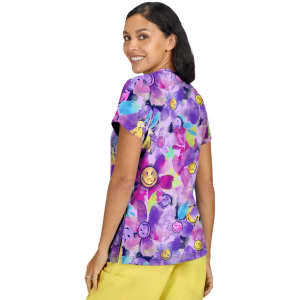 A colourful purple top featuring a playful floral and smiley face pattern, with a woman smiling while wearing it.