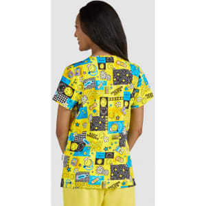 A vibrant yellow top featuring a playful print with various patterns, smiley faces, and graphic elements.