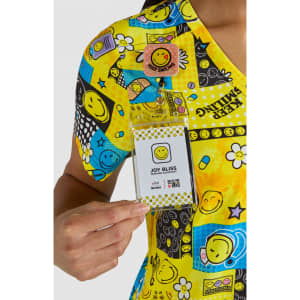 A colourful, patterned top featuring various smiley faces in yellow, with a name badge attached.