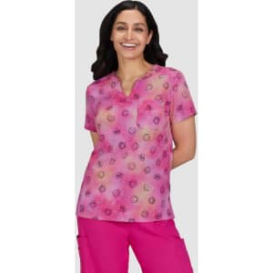 A patterned pink top featuring a V-neck and short sleeves, worn by a smiling woman.
