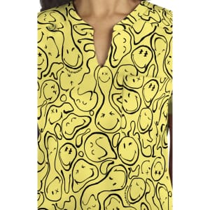 A vibrant yellow top featuring a playful print of smiling faces and abstract shapes, with a pocket detail.