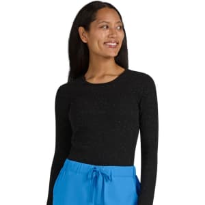 A woman wearing a long-sleeved black top with a speckled pattern, paired with blue trousers.