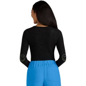 A black long-sleeve top with a speckled pattern and smiley face designs on the elbows, paired with blue pants.