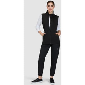 A black fleece vest featuring zippered pockets, worn over a light top, paired with coordinated black pants and shoes.