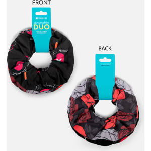 A duo set of printed scrunchies featuring black with pink lips and grey with floral designs. Includes packaging with branding.