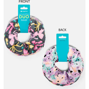 A printed scrunchie duo set featuring floral designs in pink, purple, and green, with a logo visible on the packaging.