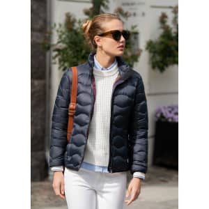 A puffer jacket in navy blue, featuring a zip front, paired with a light-coloured sweater and sunglasses.