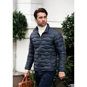 A man wears a dark grey puffer jacket, paired with a white turtleneck and holding a brown leather bag.