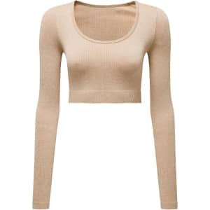 A ribbed seamless crop top in a light beige colour with long sleeves and a rounded neckline. Features a logo.