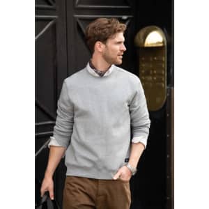 A grey unisex sweatshirt worn by a man, paired with a collared shirt and brown trousers, featuring a logo.