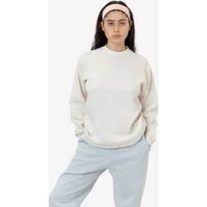A model wearing a cream-coloured heavy thermal crewneck jumper with long sleeves, paired with grey pants.
