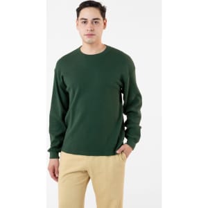 A man wearing a dark green heavy thermal crewneck jumper paired with beige trousers, featuring long sleeves.