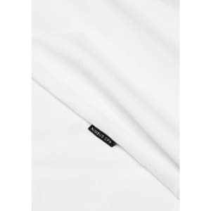 A white t-shirt with a small logo tag partially visible, set against a smooth fabric background.