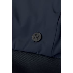 A navy hybrid jacket featuring a textured fabric and a logo badge on the front.