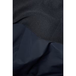 A hybrid jacket featuring a textured black upper and a smooth navy lower section, with a logo present.