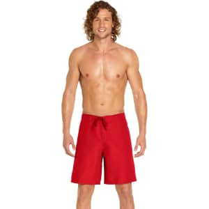 A man stands wearing red men's cargo board shorts. The shorts feature a drawstring and have a logo.