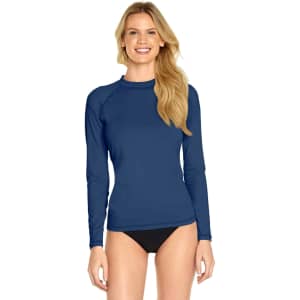 A blue long sleeve rashie with UPF 50+ protection, worn by a smiling woman. The design features a fitted silhouette.