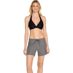 A woman is wearing grey cargo board shorts paired with a black bikini top, showcasing a relaxed fit and drawstring waist.