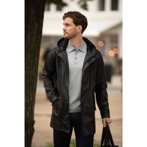 A sleek black unisex jacket with a hood, worn over a light grey polo, paired with dark jeans and a bag.