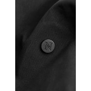 A close-up of a black fabric featuring a round black logo with an embossed letter 'N'.
