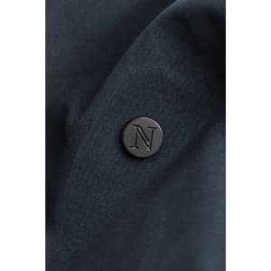 A close-up of a dark navy fabric with a round black logo badge embossed with the letter "N".