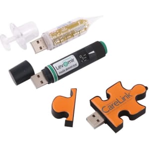 Three USB flash drives in various shapes: a syringe, an insulin pen, and a puzzle piece, featuring black, green, and orange colours.
