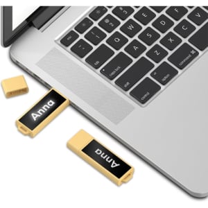 A gold LED flash drive is plugged into a laptop, with a cover next to it. The drive features a logo.
