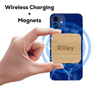 A hand holding a square bamboo wireless charger with a logo, surrounded by charging graphics on a blue phone.