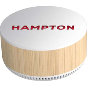A round, wireless charging speaker in white and bamboo, featuring a logo on the top.