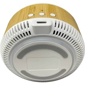 A wireless charging speaker with a bamboo exterior and a white base, featuring buttons on top and a port for charging.