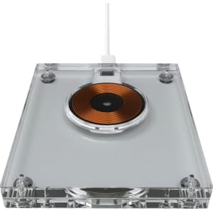 A wireless charger with a clear acrylic body and a circular copper charging pad. It includes a white charging cable.