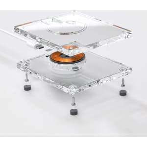 A transparent acrylic wireless charger with a circular charging pad and visible internal components.
