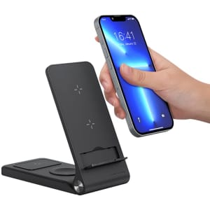 A black wireless charger with a phone being placed on it. The charger features a stand and has a logo.