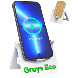 A wireless charging stand in white with a bamboo platform, holding a smartphone displaying a charging symbol.