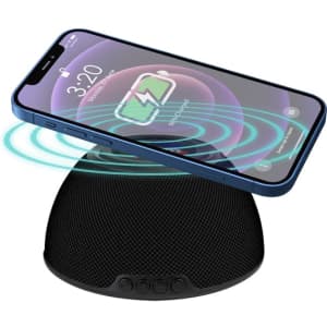 A black wireless charging speaker with a smartphone placed on top, displaying charging indicators.